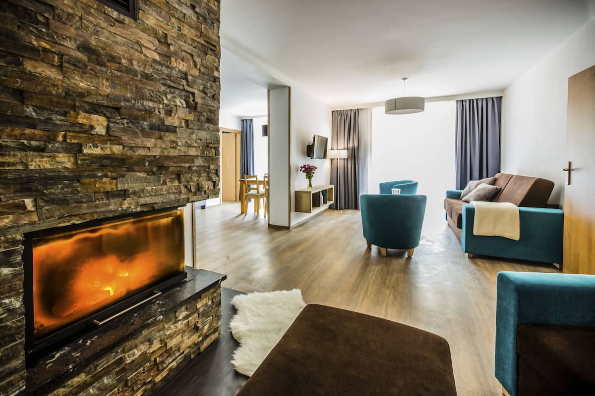 Een moderne woonkamer met een stenen openhaard, een bank, een salontafel en een eethoek.
