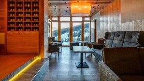Un intérieur moderne avec un présentoir à chaussures, un coin salon et de grandes fenêtres donnant sur un paysage enneigé.