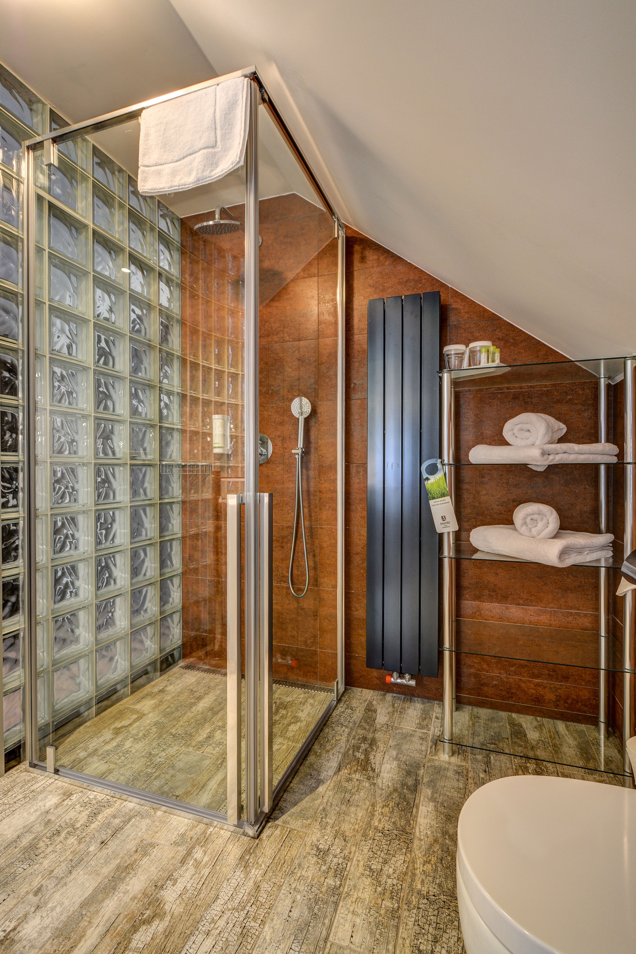 A modern bathroom with a glass shower enclosure, a wooden vanity, and a glass shower door.
