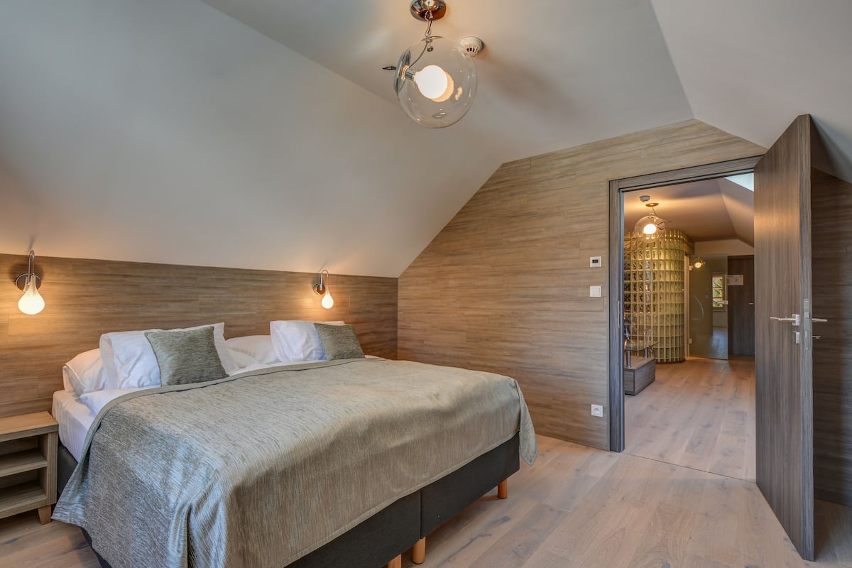 Een slaapkamer met een bed, nachtkastjes en een houten wand.