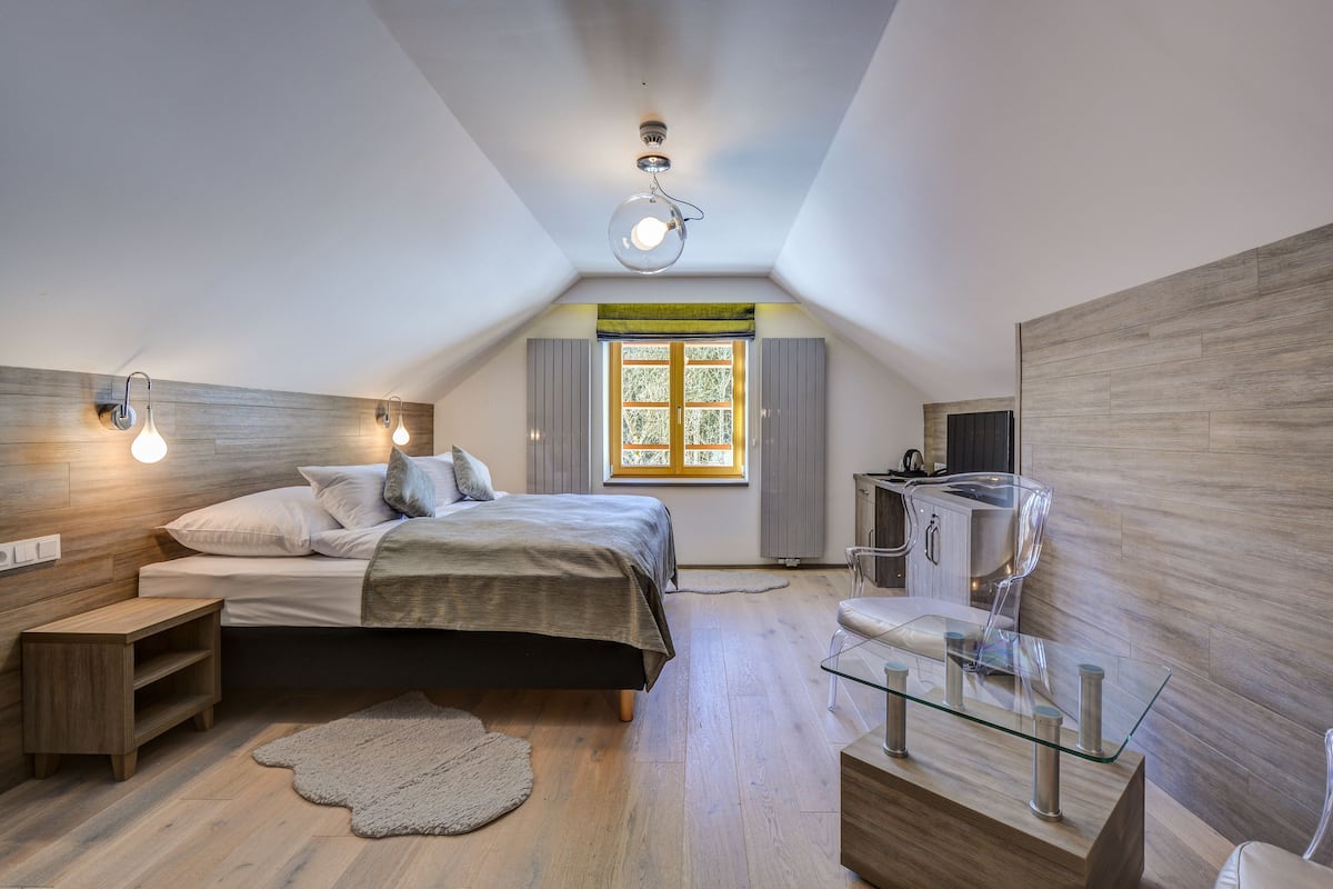Een slaapkamer met een bed, nachtkastjes, een glazen salontafel, een televisie en een raam met luiken.