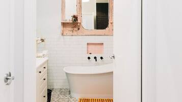 Un bagno stretto con un lavandino bianco, uno specchio e un pavimento decorato.