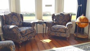 Two ornate armchairs with a floral pattern, a small table, and a globe on a stand. - The Sunfold (Weston-super-Mare)