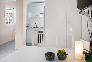 A modern kitchen with white cabinets, a sink, and a window. There is a table with two bowls of fruit and a lit candle. - 107283 - Apartment in Fuengirola (Fuengirola)