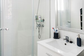 A modern bathroom with a glass shower enclosure, a white sink with a mirror above it, and toiletries on the sink. - 107283 - Apartment in Fuengirola (Fuengirola)