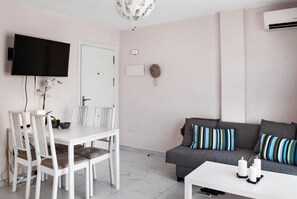A modern living room with a white dining table, grey sofa, and a flat-screen TV mounted on the wall. - 107283 - Apartment in Fuengirola (Fuengirola)