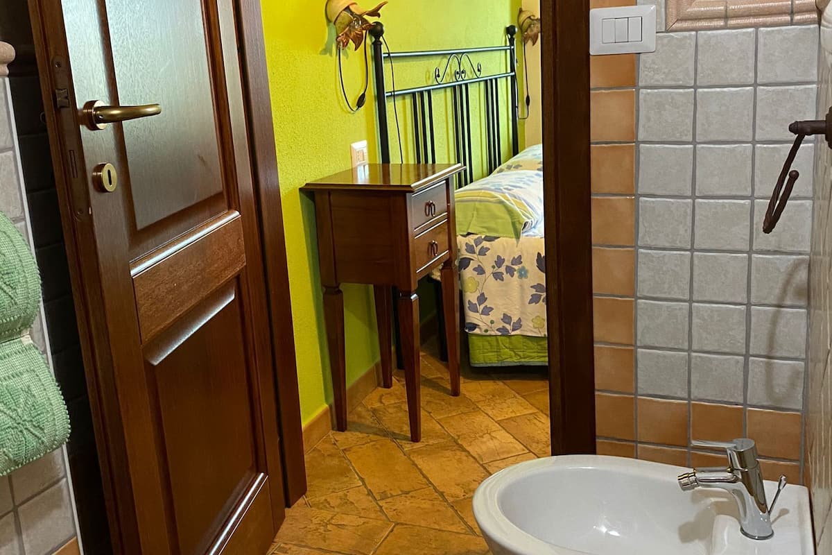 Un bagno con lavandino, toilette e un letto con comodino.