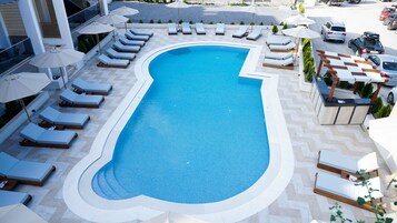 Una piscina al aire libre de temporada, sombrillas