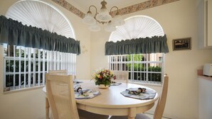 A dining area with a round table, chairs, and a chandelier.