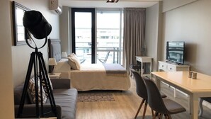 Een moderne hotelkamer met een bed, een bureau, een stoel, een bank en een statief.
