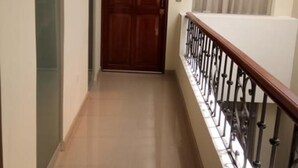 A corridor with a wooden door, a tiled floor, and a balcony railing. - Mística Boutique Hotel (Arequipa)