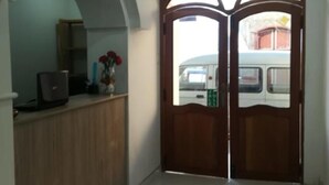 A hallway with a wooden reception desk, a tiled floor, and a double door with a window. - Mística Boutique Hotel (Arequipa)