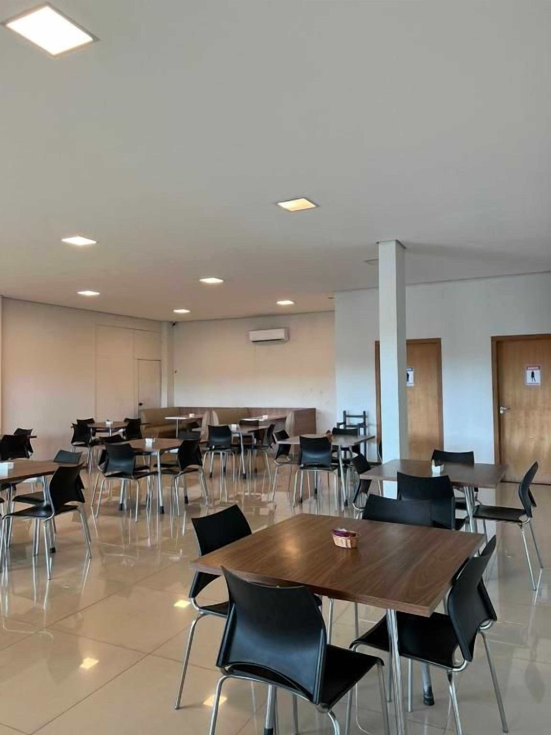 A spacious indoor area with multiple tables and chairs arranged in rows, likely a dining or meeting area.
