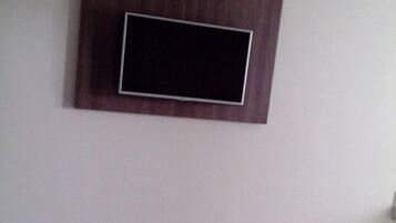 Una habitación con cama, televisión montada en la pared y un interruptor de luz.