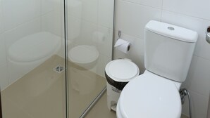 Uma casa de banho com chuveiro envolto em vidro, sanita e bidé.