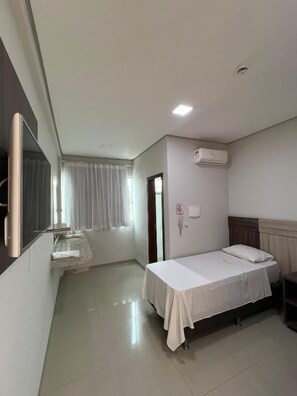 Ein Hotelzimmer mit einem Bett, einem kleinen Tisch, einem Spiegel und einer Klimaanlage.