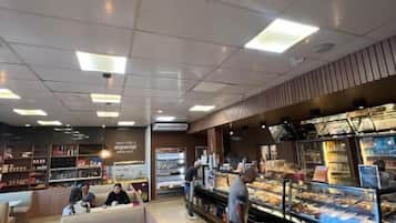 Una panadería con vitrina de productos horneados, zona de estar y mostrador para ordenar.