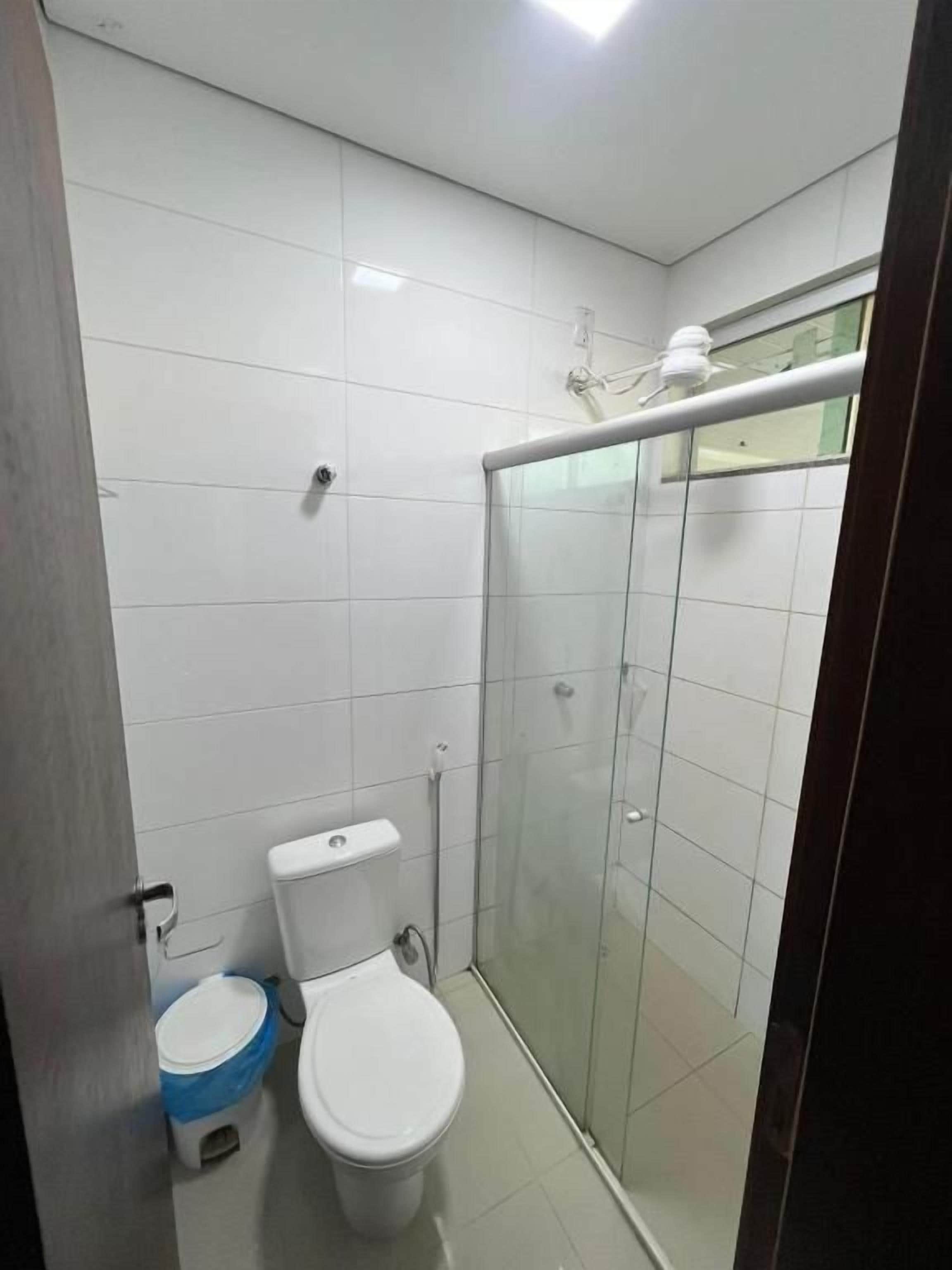 Un bany amb vàter, plat de dutxa i porta de vidre.