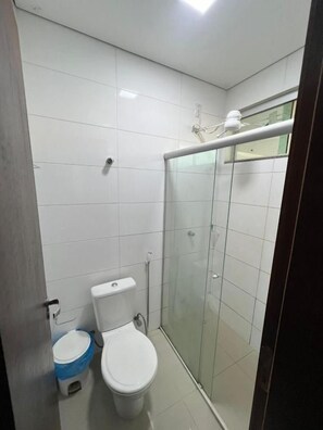 Ein Badezimmer mit Toilette, einer Duschkabine und einer Glastür.
