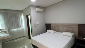 A hotel room with a large bed, a bedside table, a wardrobe, and a window with curtains.