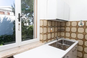 A kitchen with a window, a sink, and patterned backsplash.