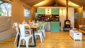 Un interior acogedor con comedor, cocina y sala de estar, que presenta suelos de madera y armarios verdes.