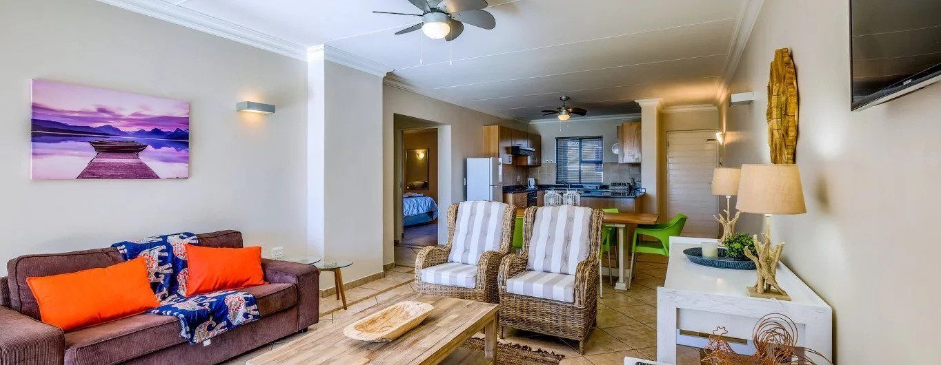 A living room with a sofa, armchairs, a coffee table, and a painting on the wall.