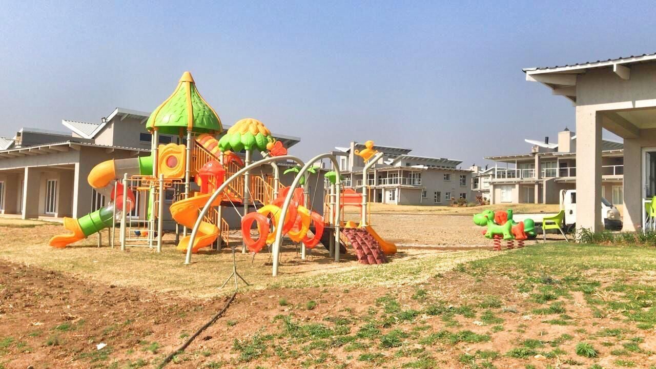Un parque infantil con toboganes y estructuras para escalar, rodeado de edificios residenciales.