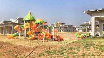 Un parque infantil con toboganes y estructuras para escalar, rodeado de edificios residenciales.