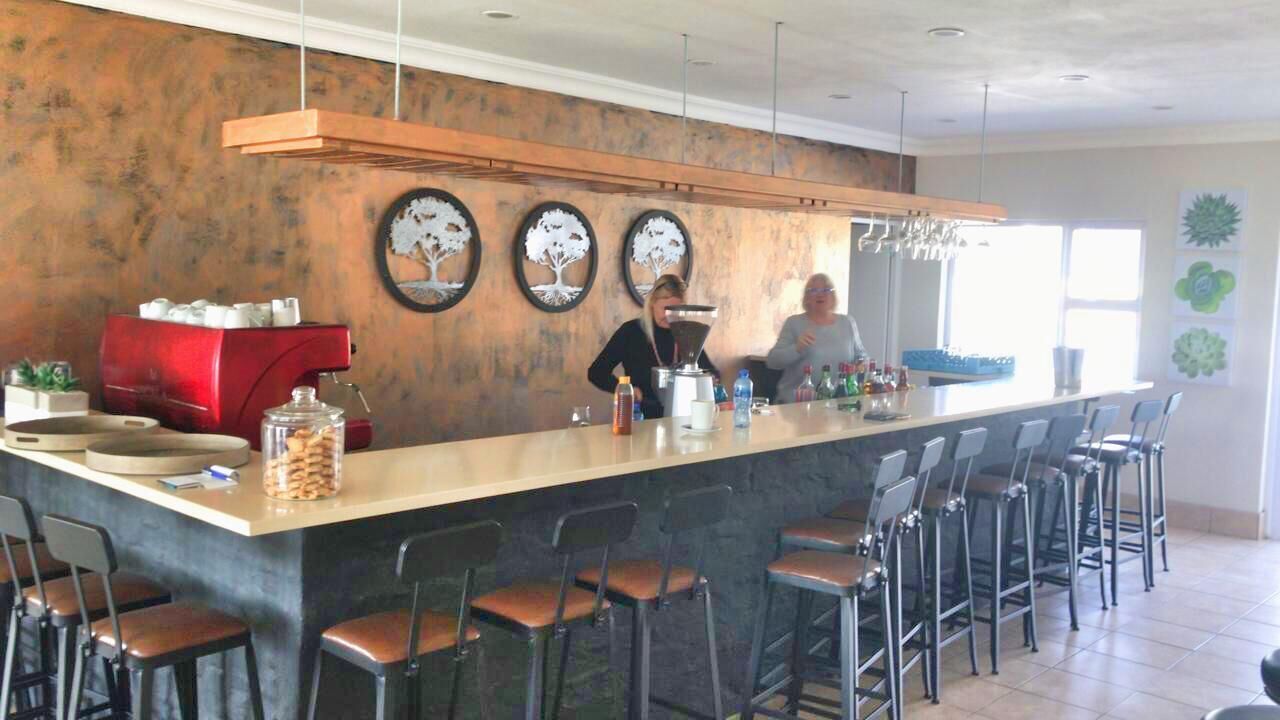 A bar area with a counter, stools, and a coffee machine.