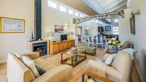 A spacious living room with a fireplace, comfortable seating, and a dining area visible in the background. - The Anchorage (Vaal Marina)