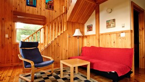 A wooden interior with a blue chair, a red sofa, and a small table.