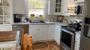 A kitchen with white cabinetry, a wooden dining table, and a built-in oven. - Beautiful water's edge 2 bedroom vacation home (Breadalbane)