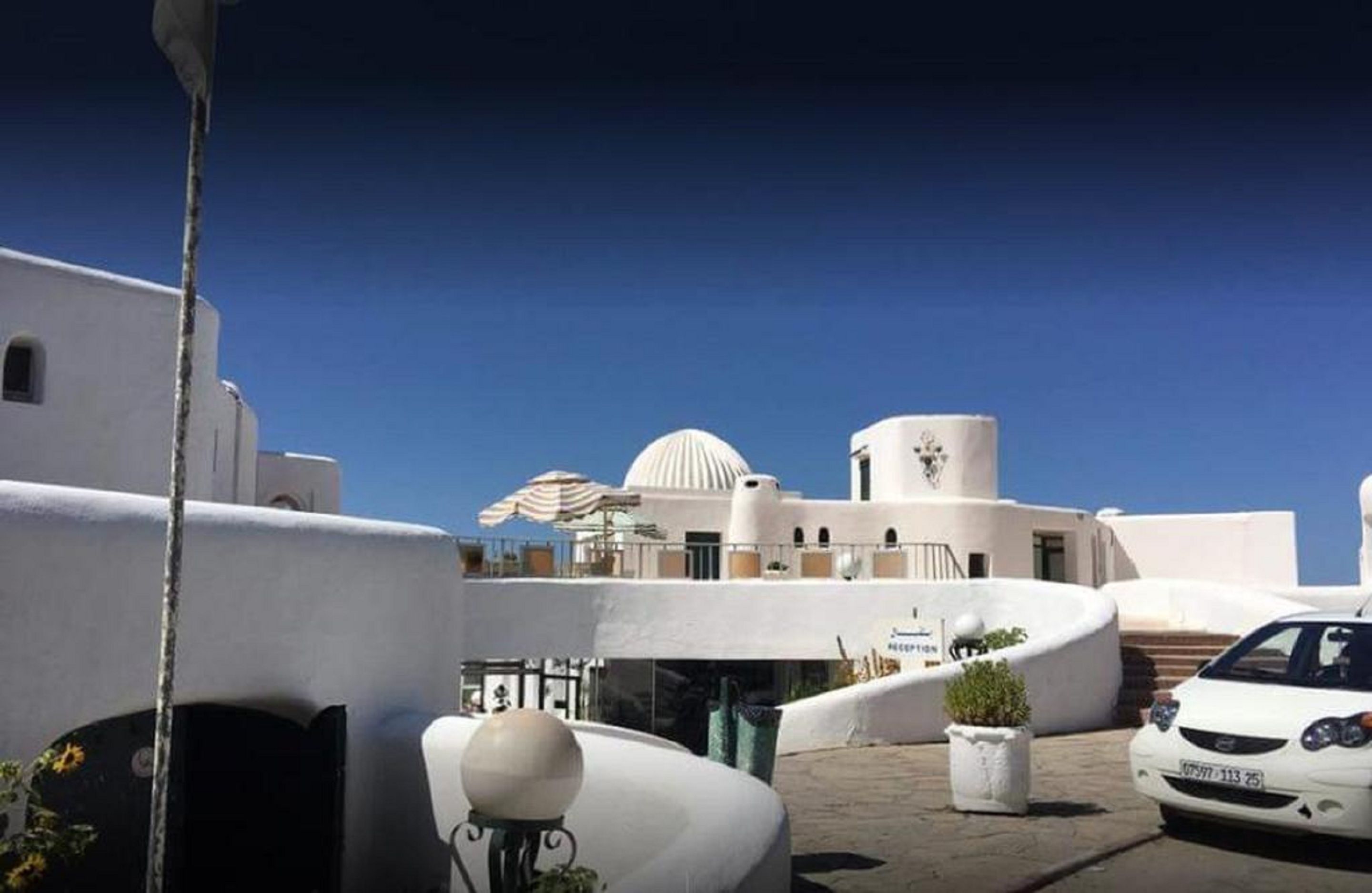 A white building with a dome and a cylindrical structure, possibly a hotel or resort.