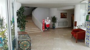 Ein geräumiger Wohnbereich mit einer Treppe zu einer weiteren Etage, einem roten Sessel und einer Topfpflanze.