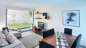 Ett modernt vardagsrum med en soffa, TV, matbord och konstverk.