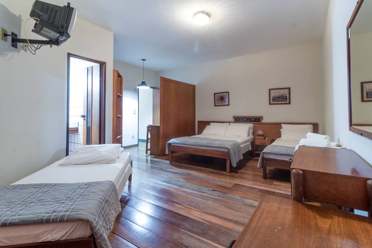 Habitación de hotel con dos camas, suelo de madera, un escritorio y un espejo.