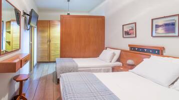 A hotel room with two beds, wooden wardrobe, a TV mounted on the wall, and framed pictures on the wall.
