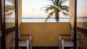 A room with a view of a palm tree and a body of water. - Hotel Praia Sol (Serra)