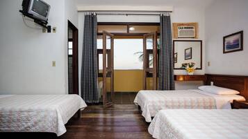 Habitación de hotel con dos camas, televisión, ventana con cortinas, piso de madera y vistas al exterior.