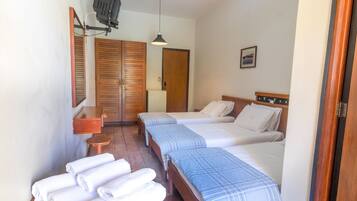 A hotel room with two beds, a wooden wardrobe, a small table, and a mirror.