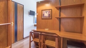 A wooden dining area with a table and chairs, a framed picture on the wall, and a television mounted on the wall. - Hotel Praia Sol (Serra)