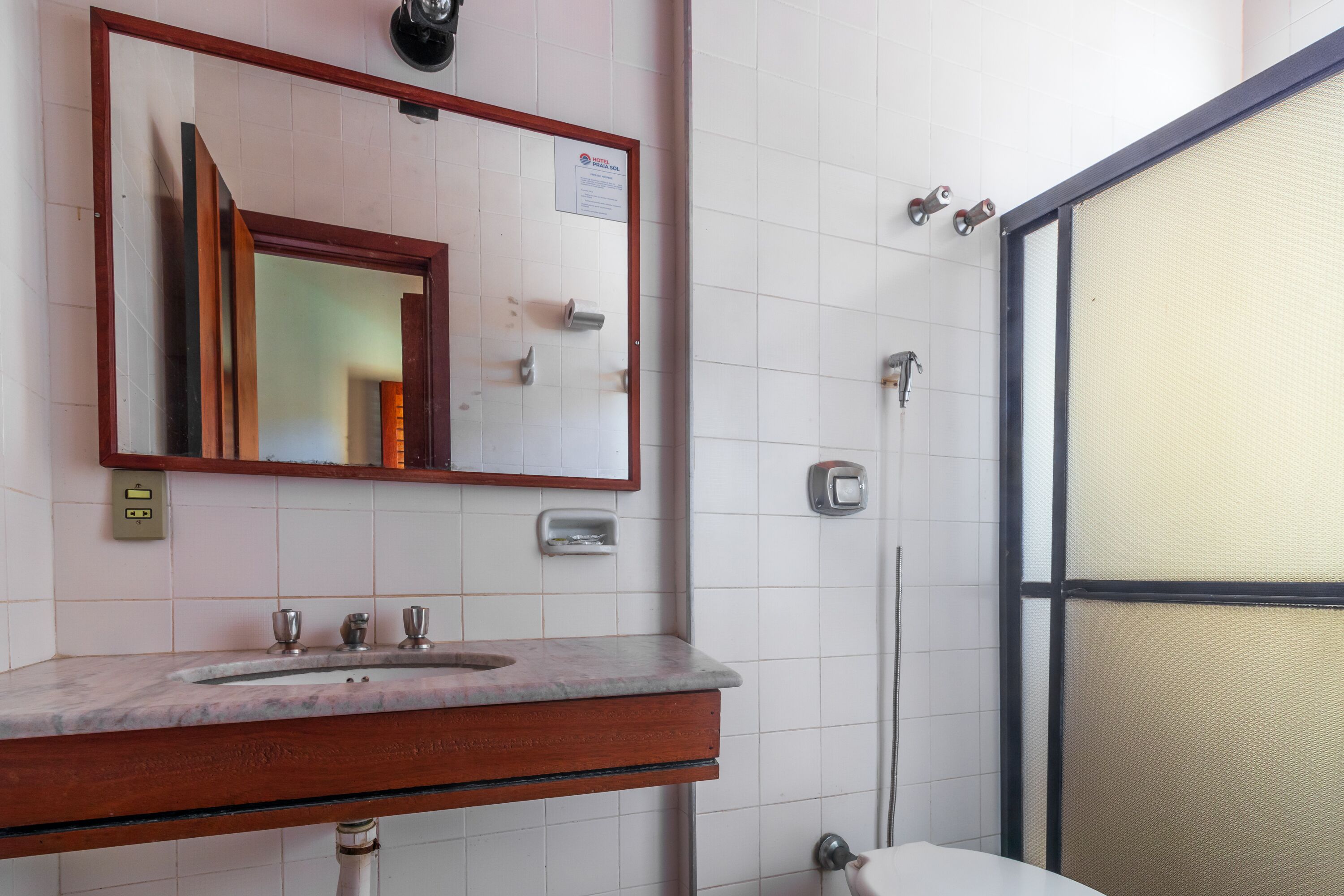 Un baño con tocador de madera, espejo, lavabo y zona de ducha.