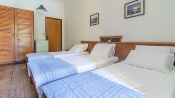 A hotel room with two beds, wooden wardrobe, and a picture on the wall.