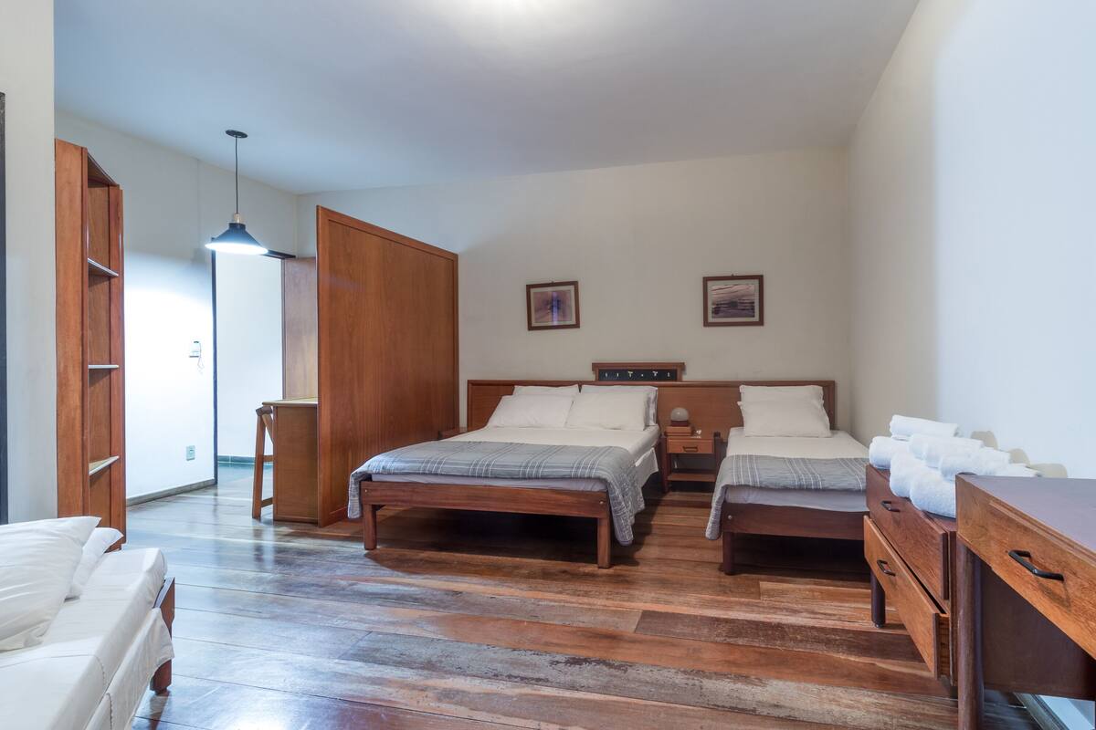 Un dormitorio con dos camas, suelo de madera, un armario y un escritorio.