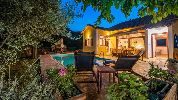 Et poolområde med liggestole, en swimmingpool og et hus med åben terrasse.