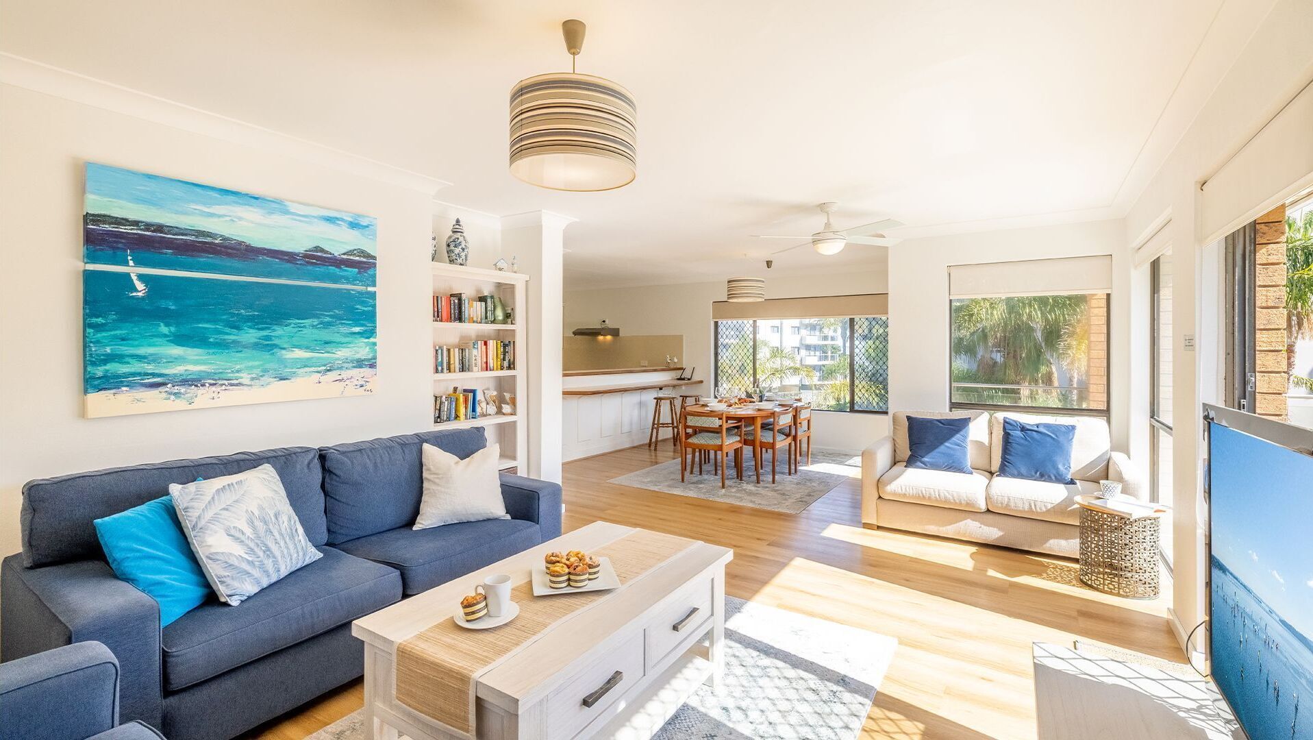 Ein modernes Wohnzimmer mit einer Couch, einem Couchtisch und einem Bild einer Strandlandschaft.