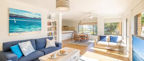 Ein modernes Wohnzimmer mit einer Couch, einem Couchtisch und einem Bild einer Strandlandschaft.