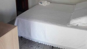 A bedroom with a bed, a wooden door, a mirror, and a wall-mounted air conditioner. - Pousada Vila Velha (Pirenópolis)
