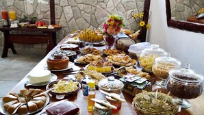 A buffet table with various food items and condiments. - Pousada Vila Velha (Pirenópolis)